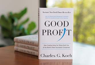 A hardcover copy of Good Profit by Charles Koch, standing upright against a neutral gradient background.