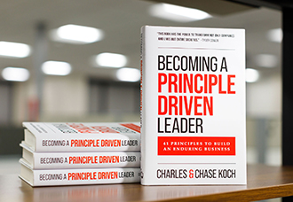 A hardcover copy of Becoming a Principle-Driven Leader, co-authored by Charles Koch and Chase Koch, standing upright against a neutral gradient background.