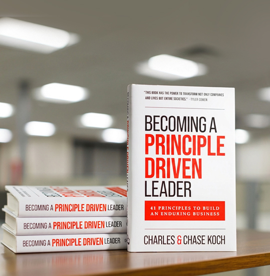 A hardcover copy of Becoming a Principle-Driven Leader, co-authored by Charles Koch and Chase Koch, standing upright against a neutral gradient background.