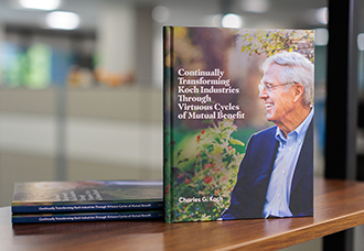 A hardcover copy of Continually Transforming Koch Industries Through Virtuous Cycles of Mutual Benefit by Charles Koch.