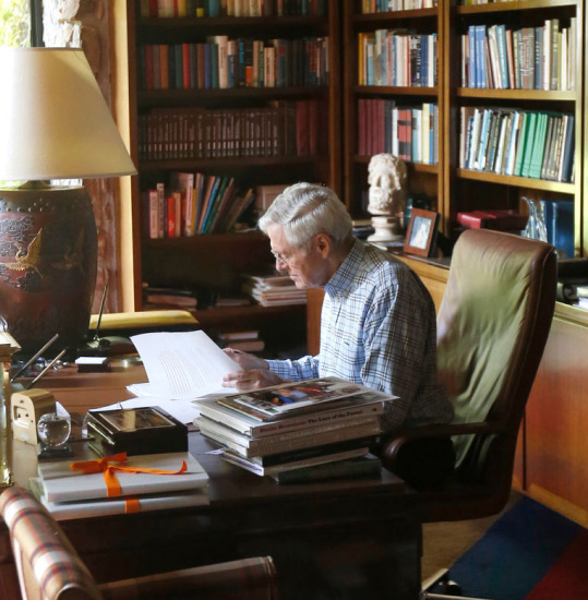 Charles Koch sitting at a desk reading a book